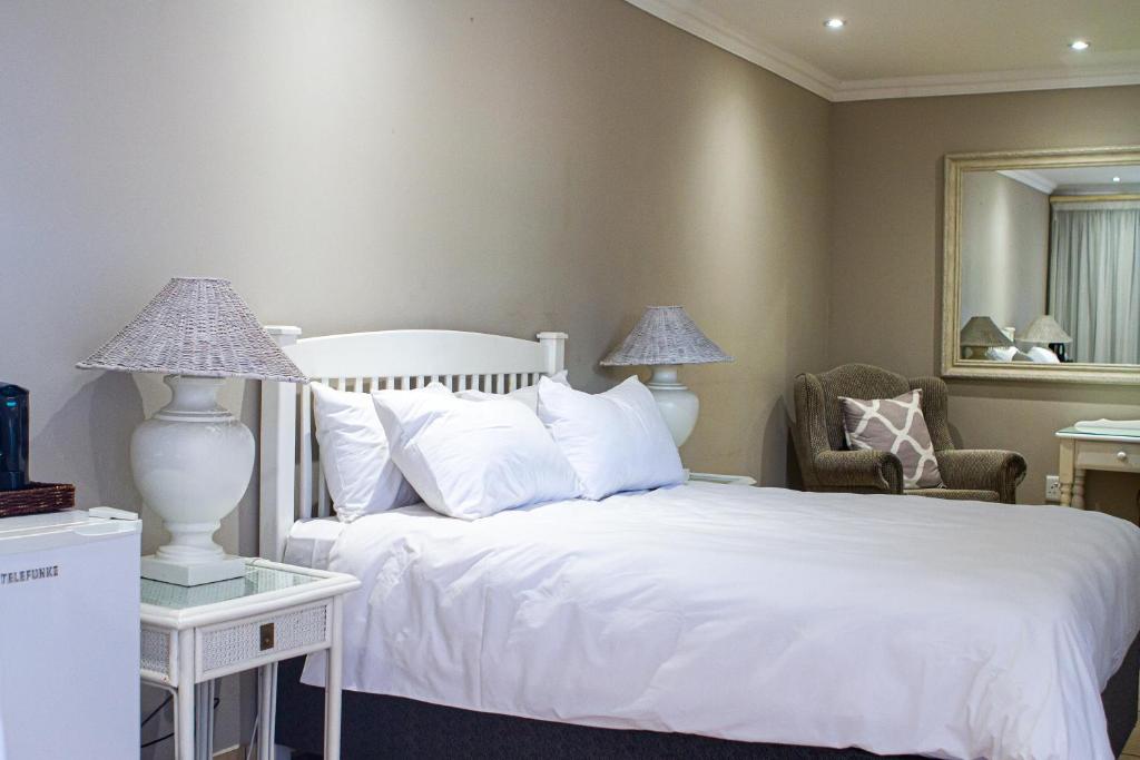 LephalaleMachauka Lodge的卧室配有白色的床、椅子和镜子