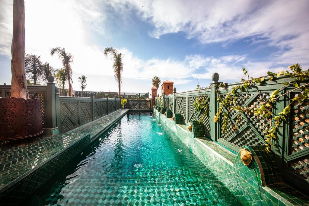 马拉喀什Elegancia Riad Boutique & SPA的一座拥有蓝色海水和棕榈树的游泳池