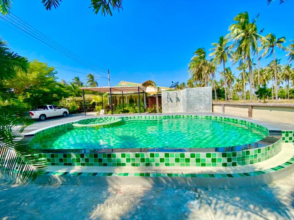 班武里府ศรีสุภาวดีรีสอร์ท-Srisupawadee resort的一座位于度假村内的游泳池,后面设有停车场
