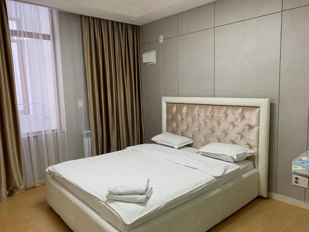 阿斯塔纳Highvill AST的卧室配有一张带白色床单和枕头的大床。
