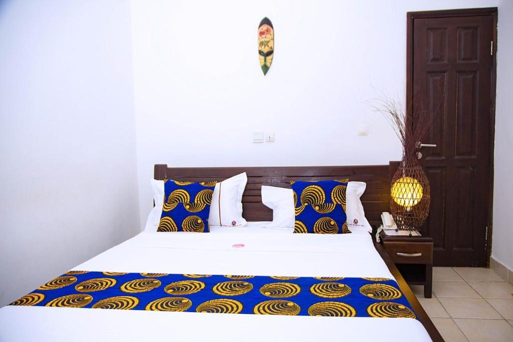 阿比让塞帕酒店的一间卧室配有一张带蓝色和黄色枕头的大床
