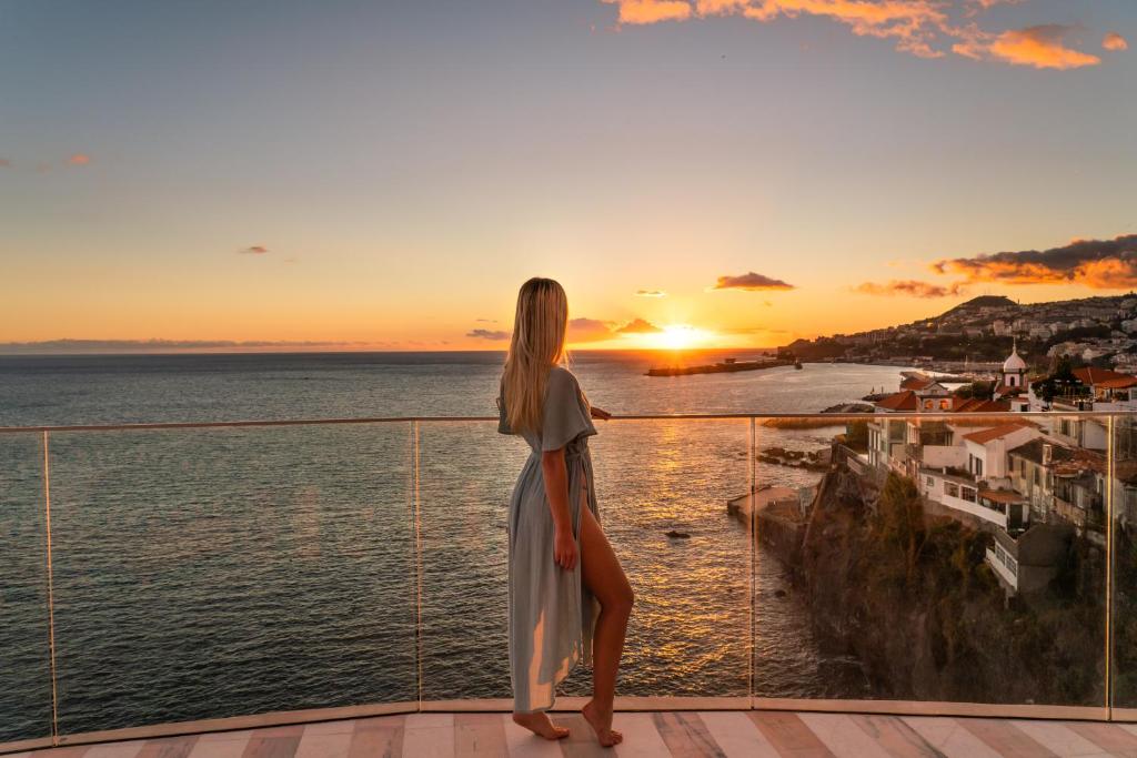 丰沙尔Okulus Madeira的站在阳台上欣赏日落的女人