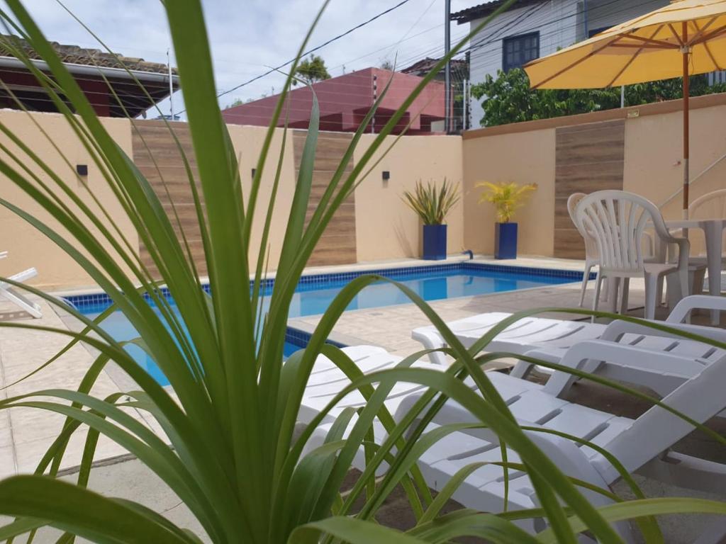 阿拉亚尔达茹达Pousada Cheiro de Cacau的房屋旁的游泳池配有椅子和遮阳伞