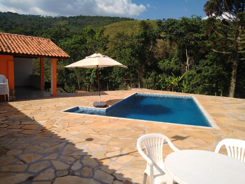卡皮托利乌Sítio Pé da Serra - Pousada Rural的一个带遮阳伞和桌椅的游泳池