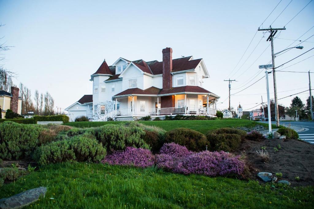 库珀维尔安克雷奇住宿加早餐旅馆的一座白色的大房子,带紫色花的院子