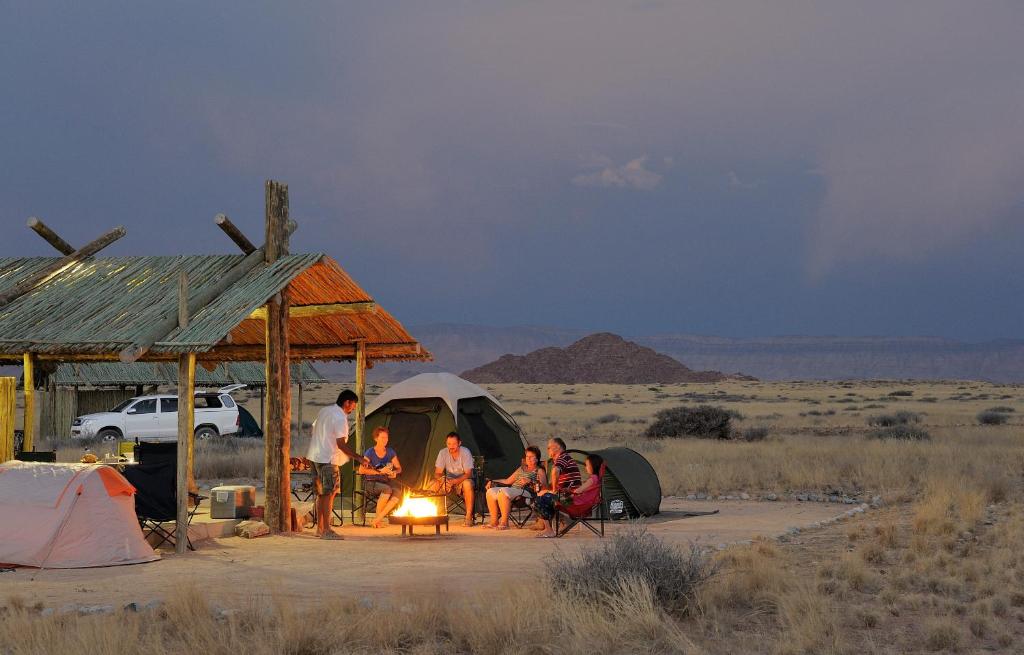 塞斯瑞姆Sossus Oasis Campsite的一群人坐在沙漠的帐篷周围