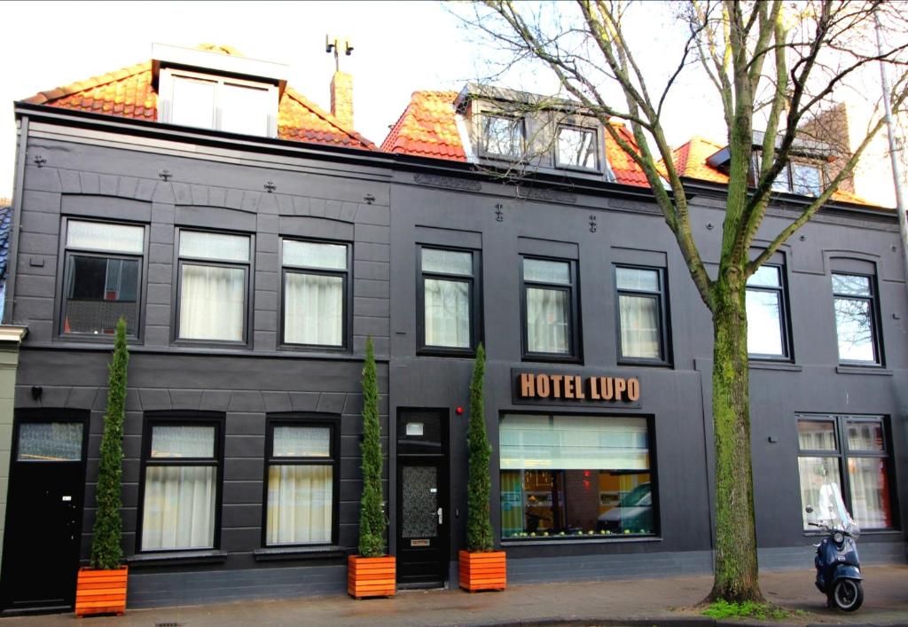 弗利辛恩Boutique Hotel Lupo的一座黑色的建筑,前面停有一辆摩托车