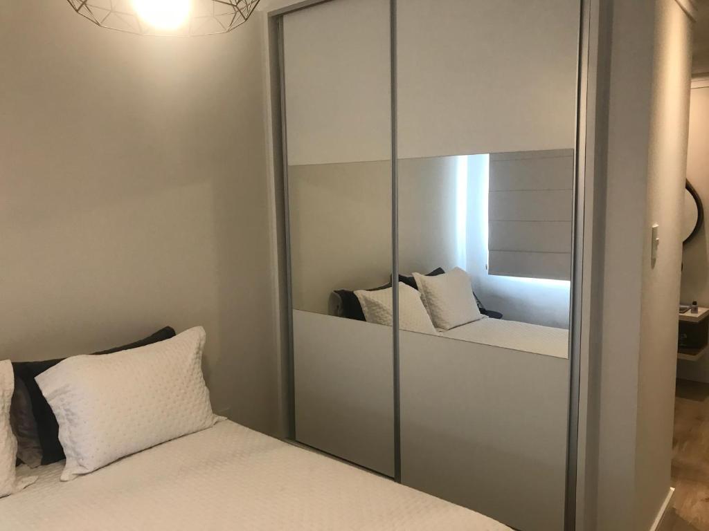 桑托斯Apartamento Frente ao Mar Santos的一间卧室配有镜子和一张带白色枕头的床