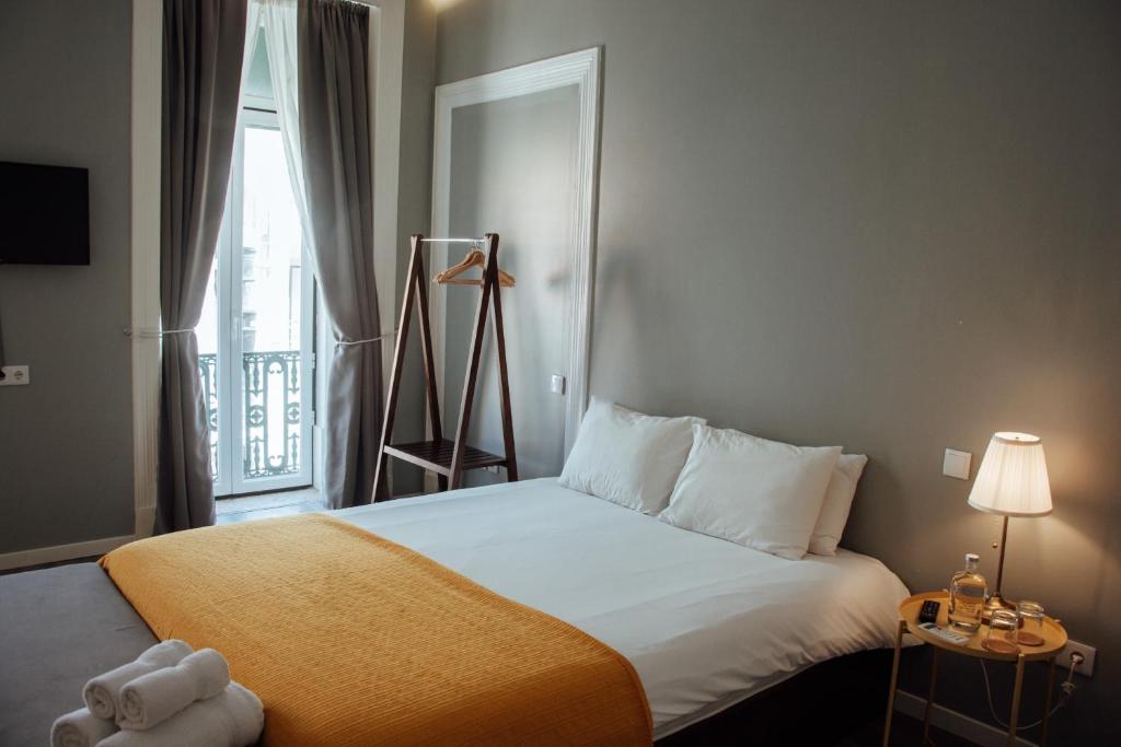 里斯本The Hygge Lisbon Suites - Estrela的一间卧室设有一张大床和窗户