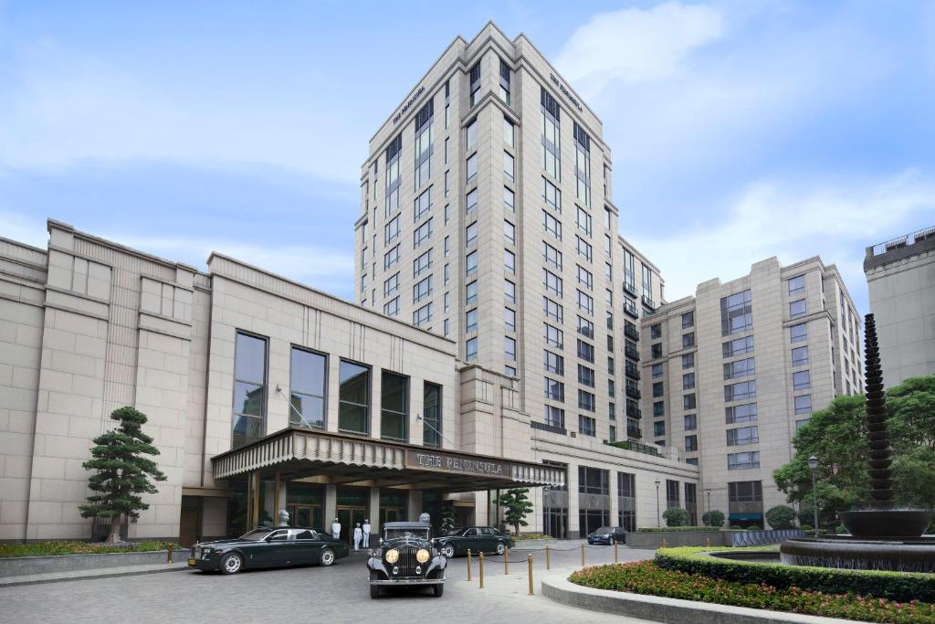 上海上海半岛酒店的一座大型建筑,前面有汽车停放