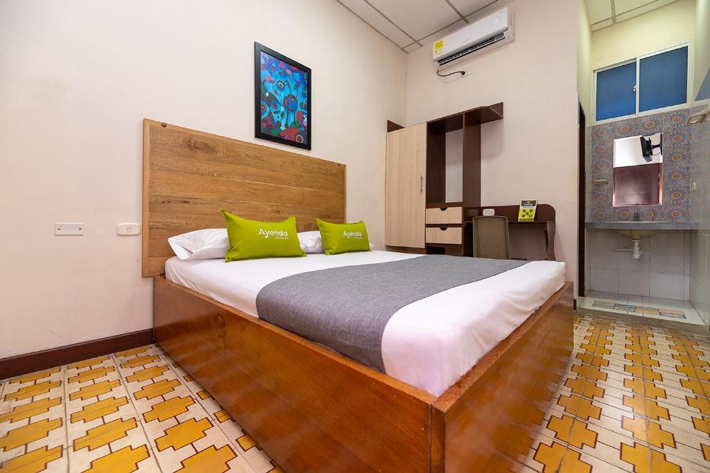 巴兰基亚Hotel Ayenda Skall 1319的一间卧室配有一张带绿色枕头的大床