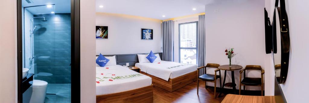 归仁KADUPUL HOTEL的客房设有两张床、一张桌子和一扇窗户。