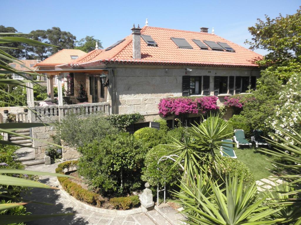 维戈Hotel Playa Samil Vigo的一座有红色屋顶和一些植物的房子