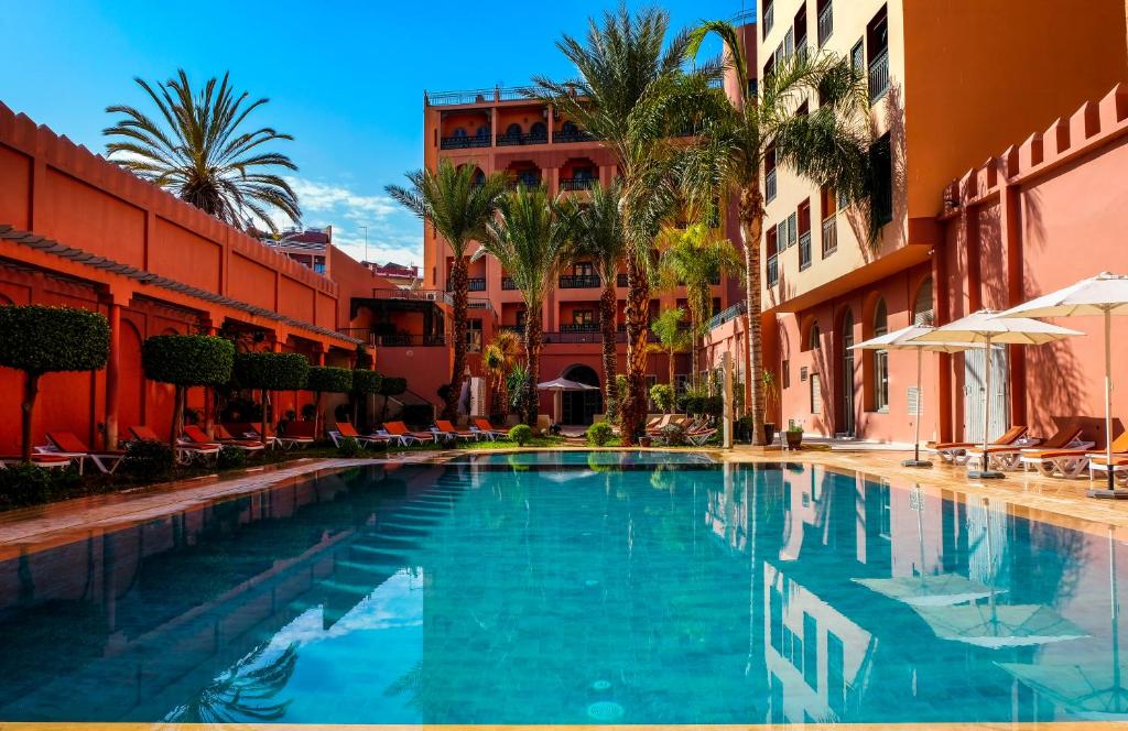 马拉喀什戴文酒店＆马拉喀什Spa的棕榈树和建筑度假村内的游泳池