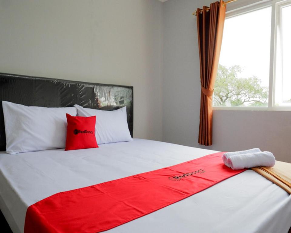 AlastuwoRedDoorz @ City Park Medoho Semarang的一张带红色和白色枕头的床和窗户
