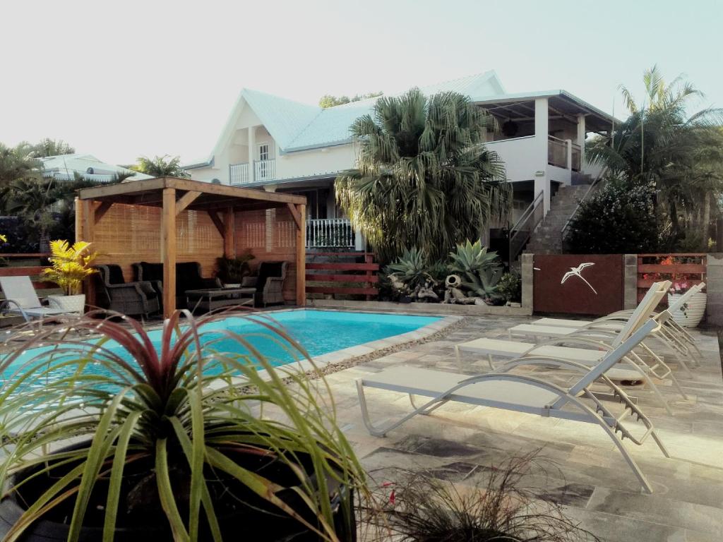 圣玛丽LE COLONIAL, T4 à 5 mn Aeroport dans villa de standing的一个带游泳池和房子的后院