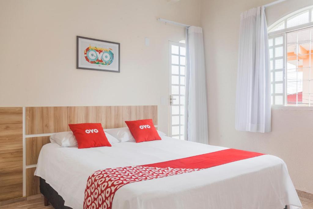 巴西利亚OYO Hotel Brisa Tropical, Brasília的卧室配有带红色枕头的大型白色床