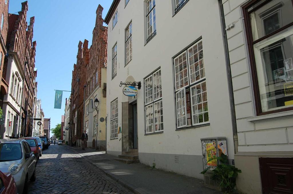 吕贝克吕贝克老城青年旅舍的一条有建筑和汽车停在鹅卵石街道上的街道