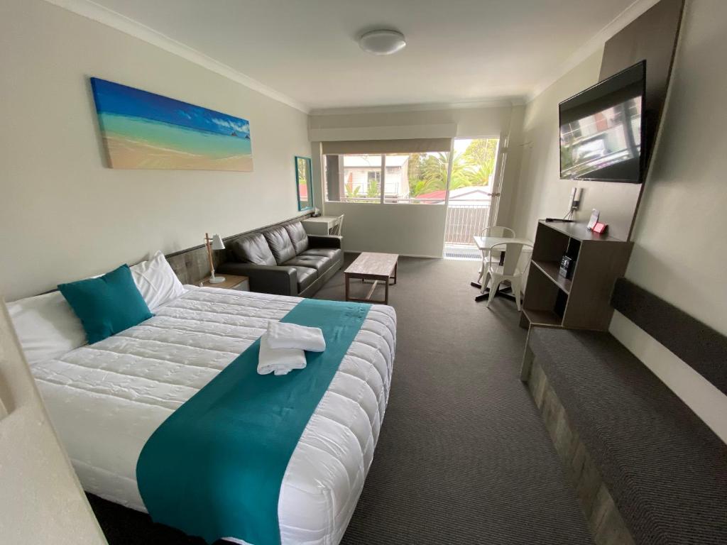 纳鲁马陶坡唐汽车旅馆的酒店客房设有一张大床和一张沙发。