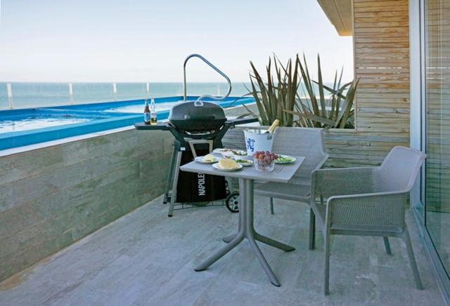埃斯特角城SYRAH Piscina Privada y Vista al Mar en Punta Ballena的露台上的烧烤架,配有桌椅