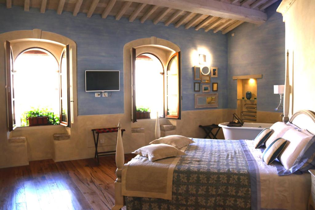 皮恩扎Il Mastio di Spedaletto的一间卧室配有一张带两个窗户的床和一台电视
