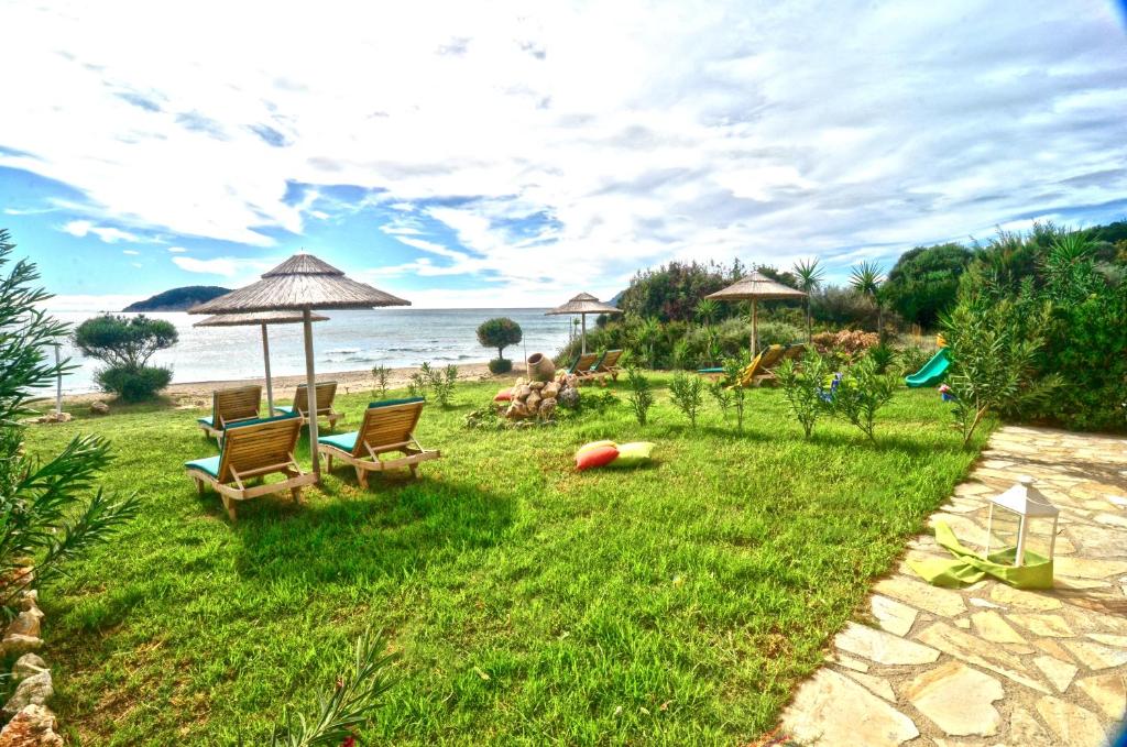 瓦西里科斯Beachfront Elena Villa with mini pool and spa的海滩上带椅子和遮阳伞的草坪