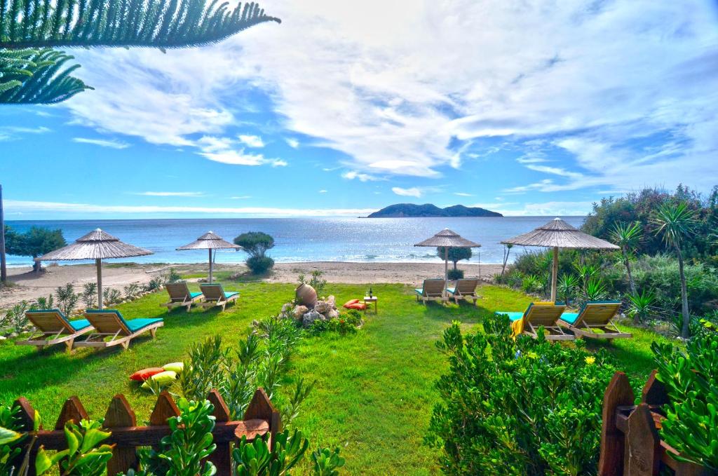 瓦西里科斯Beachfront Andriana Villa with mini pool and spa的海滩上带椅子和遮阳伞的草坪