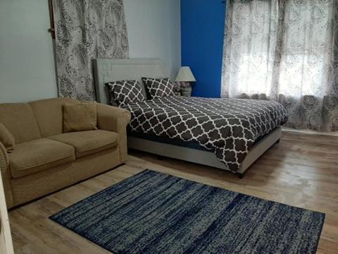 温尼伯Close to center的一间卧室配有床、沙发和地毯。
