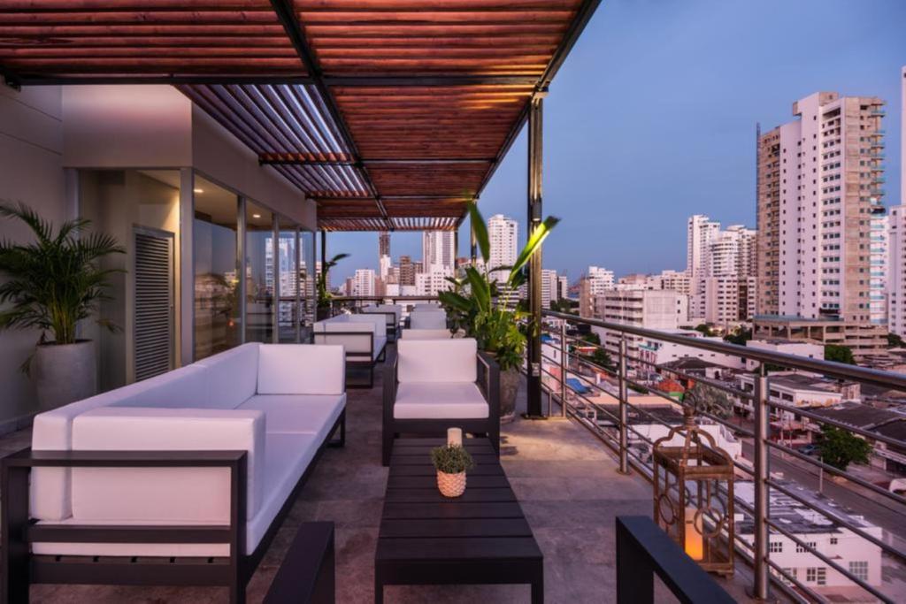 卡塔赫纳Oz Hotel Luxury的屋顶庭院配有白色家具,享有城市美景。
