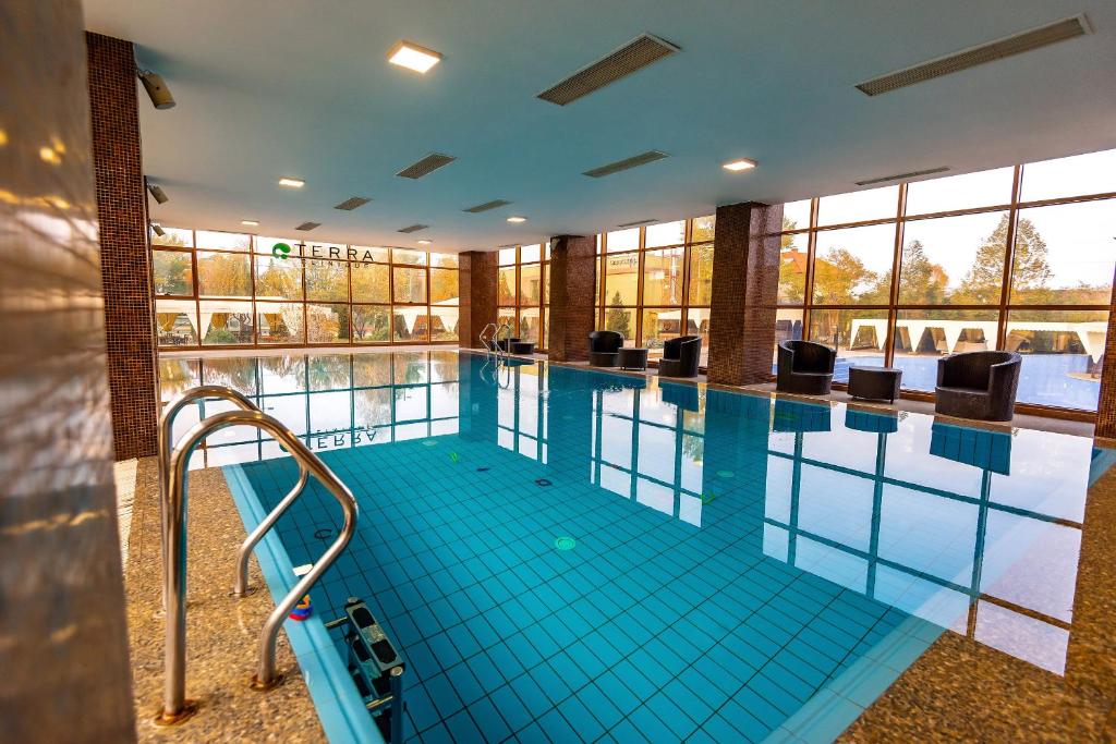 加拉茨Hotel Terra Balneo&Spa的大型游泳池设有蓝色瓷砖地板和窗户。