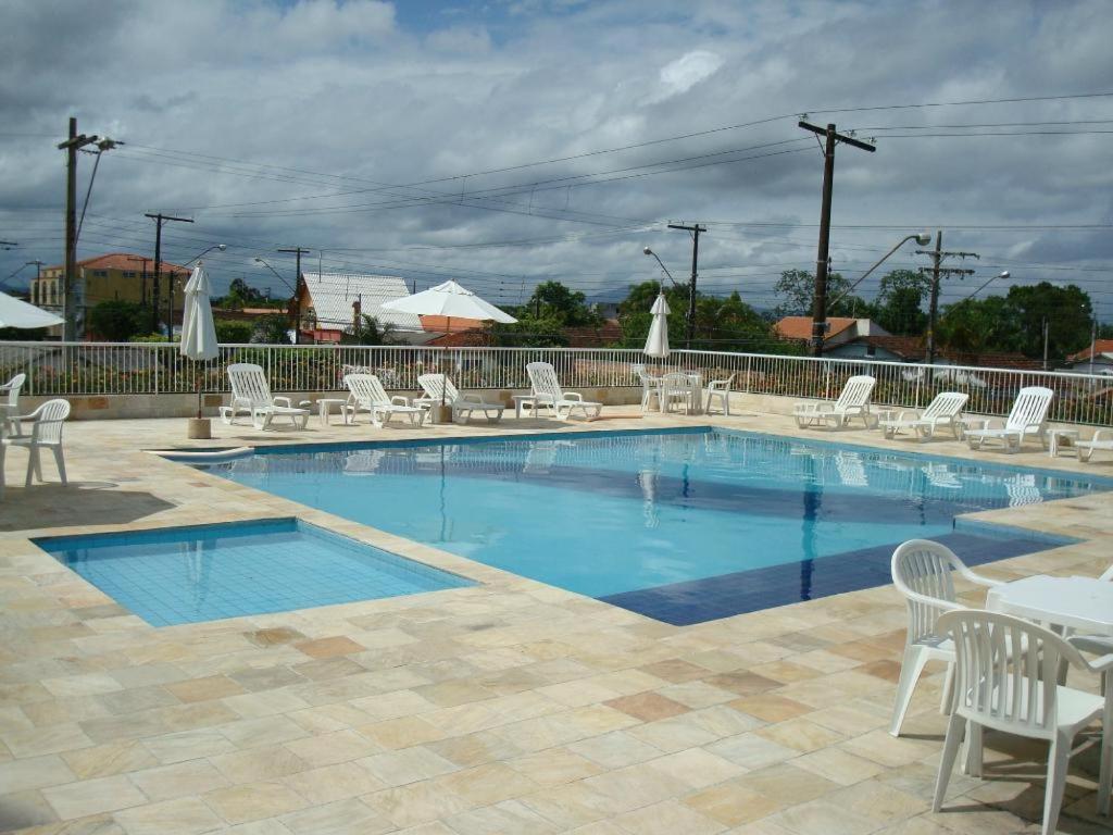 卡纳内亚Golfinho Plaza Hotel的游泳池配有白色的桌椅