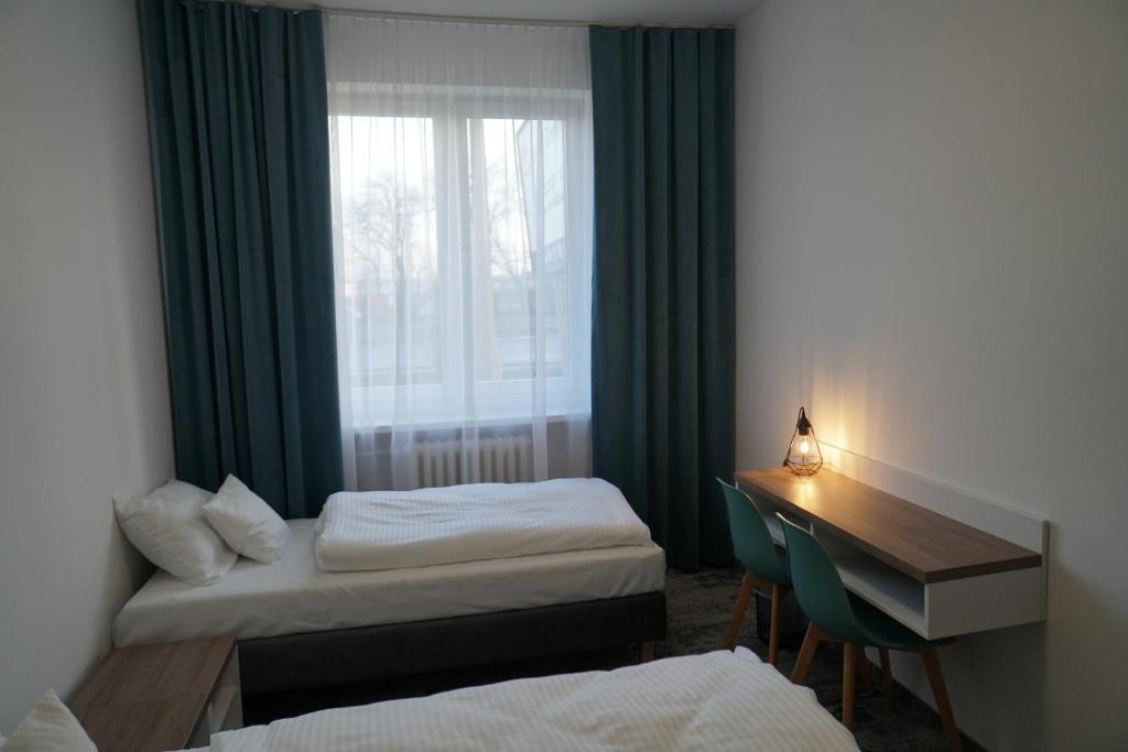 科沙林Stary Koszalin Hostel &amp; Hotel Services的有两张床、一张书桌和一扇窗户的房间