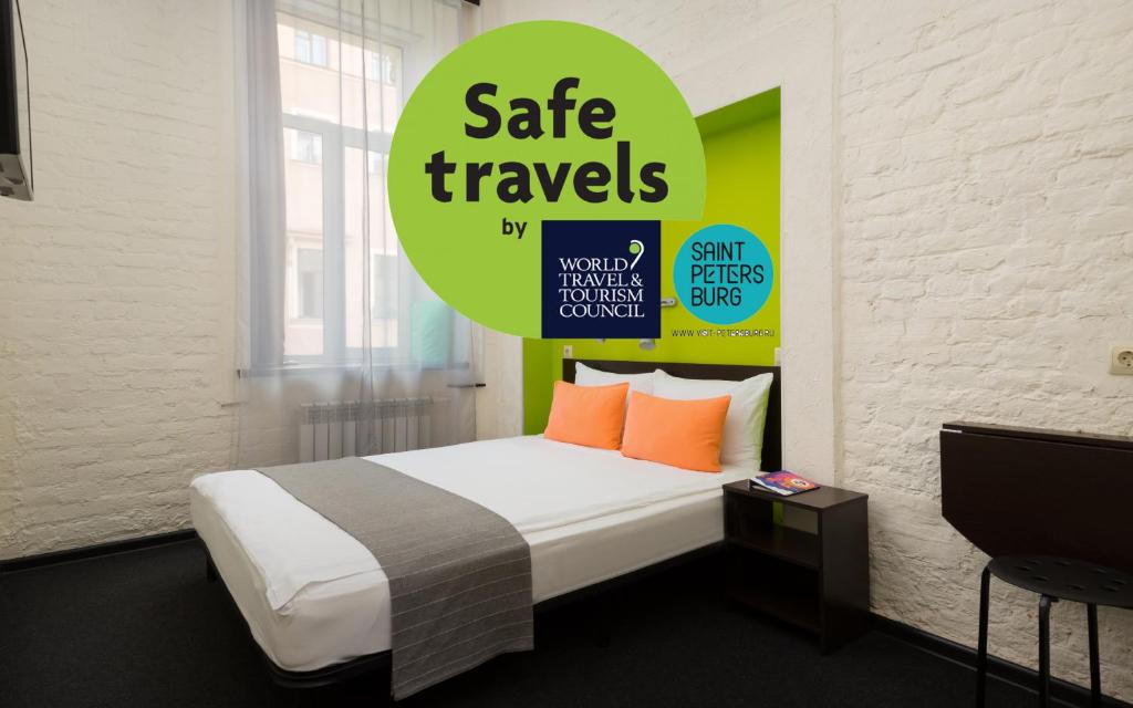 圣彼得堡S13站酒店的一间卧室,配有一张带安全旅行标志的床