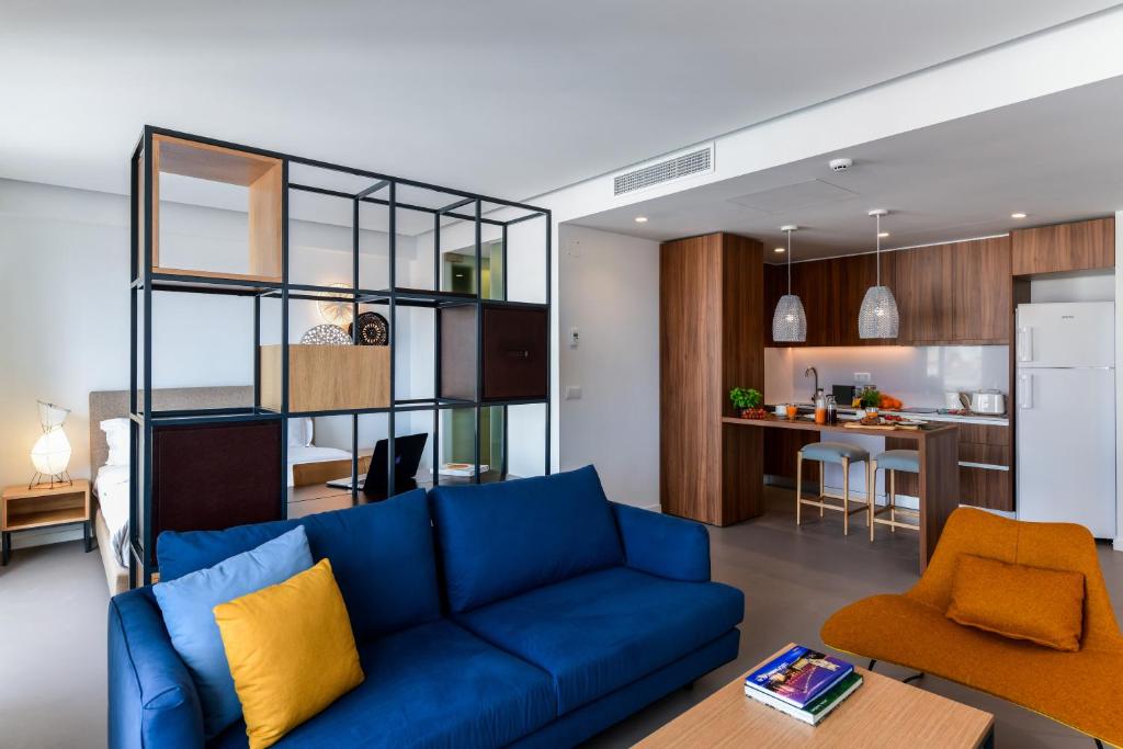 里斯本Oscar Concept Apartments的一间带蓝色沙发的客厅和一间厨房