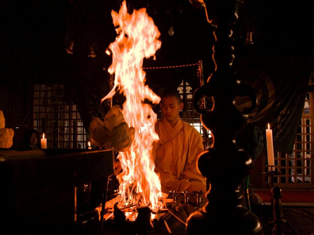 高野山高野山 宿坊 恵光院 -Koyasan Syukubo Ekoin Temple-的坐在火前的人
