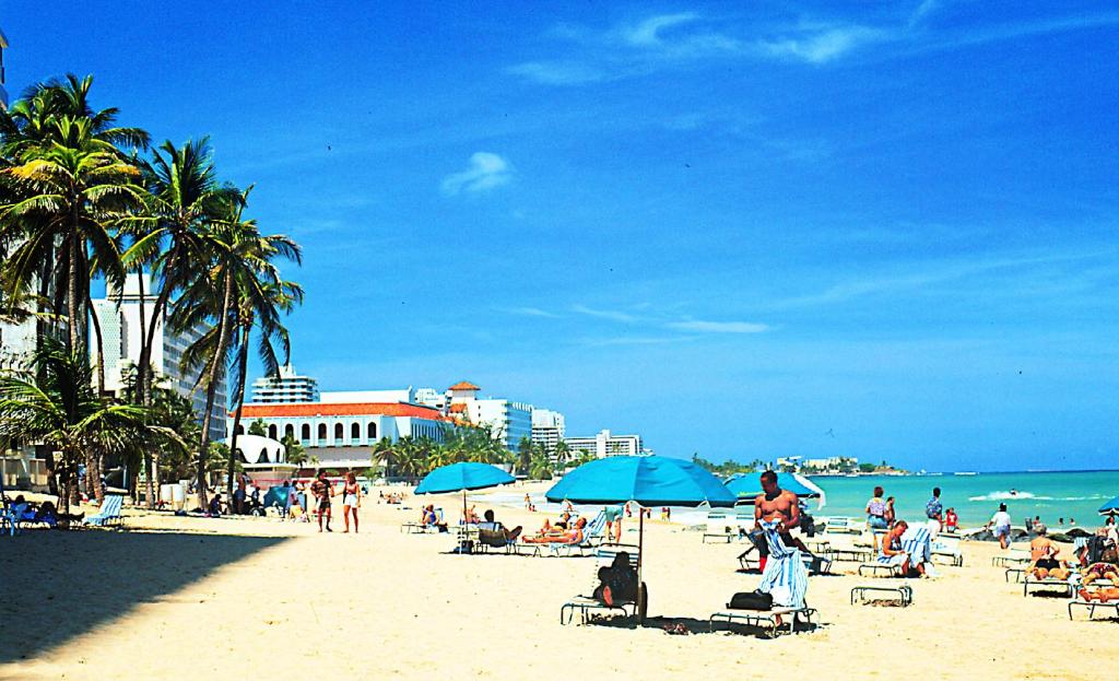 圣胡安卡纳里奥精品酒店的一群人,在海滩上,用蓝伞