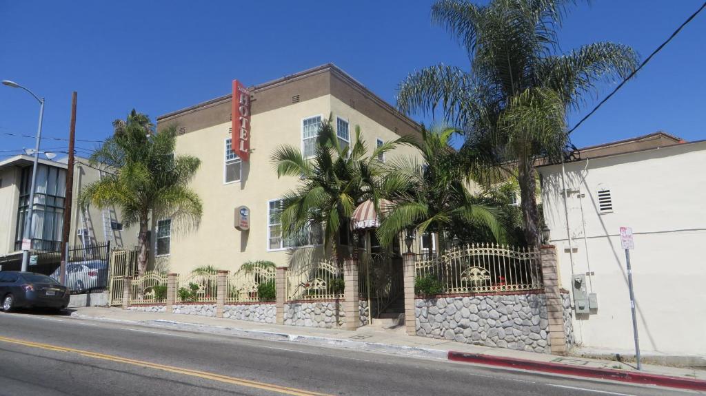 洛杉矶特里隆酒店 - 好莱坞的街道前方有棕榈树的建筑