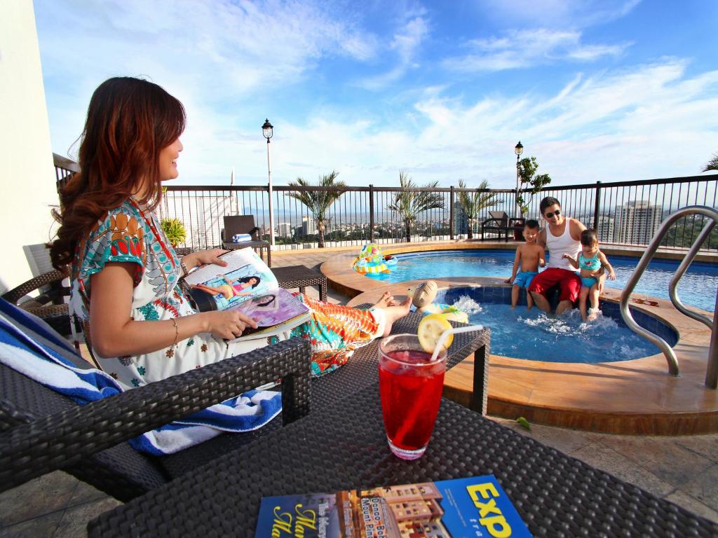 马尼拉Parque España Residence Hotel Managed by HII的坐在游泳池前桌边的女人