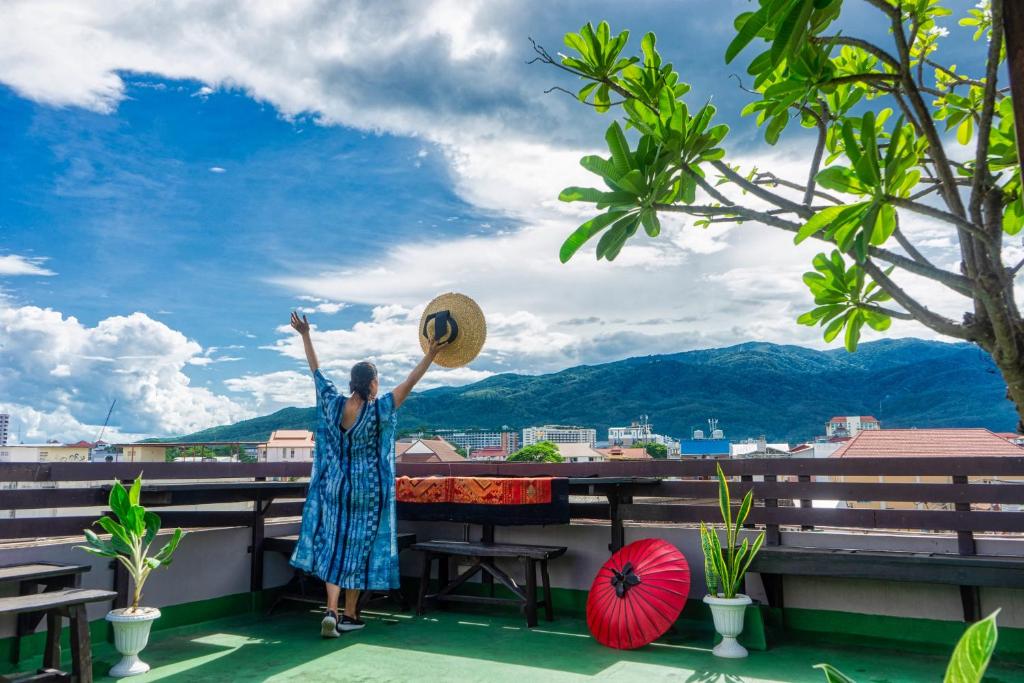 清迈Ban Kong Rao Guesthouse的站在阳台上的女人,手放在空中