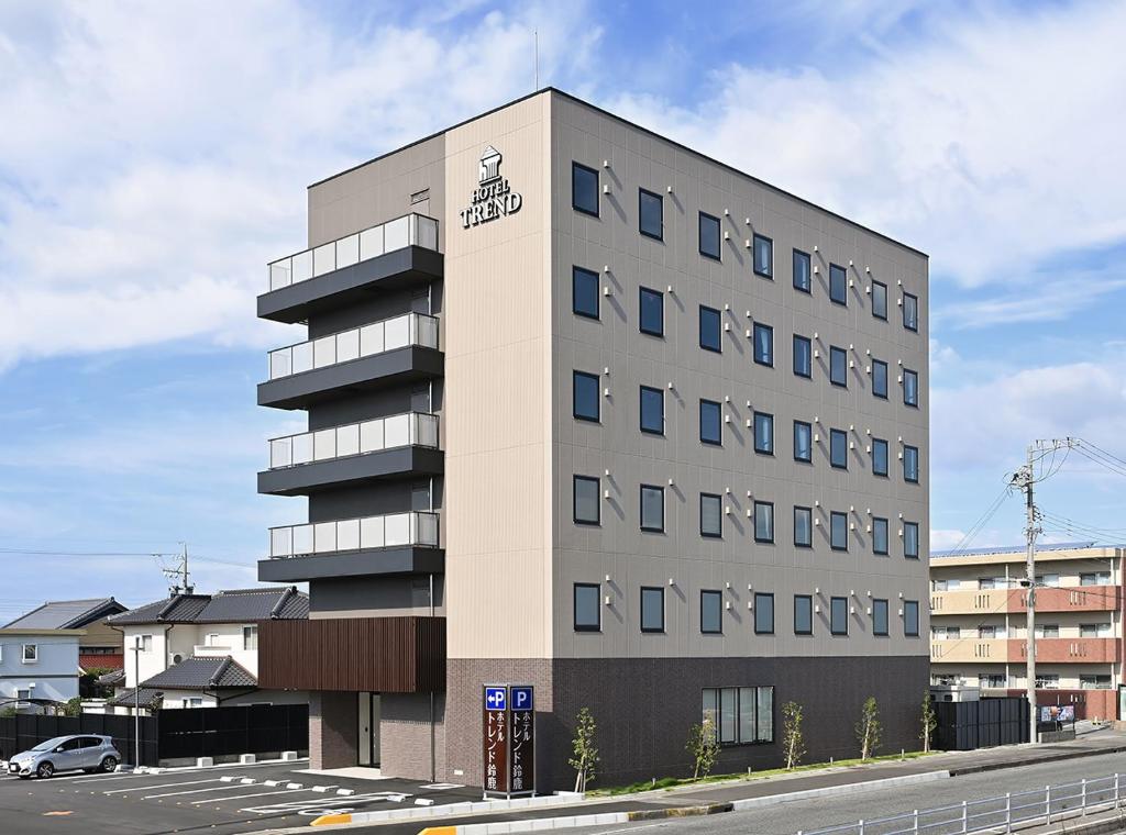 铃鹿市Hotel Trend Suzuka的一座高大的建筑,前面有一辆汽车