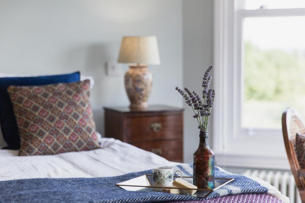 瓦伊河畔罗斯Bridstow Guest House的一张带桌子的床铺,上面有盘子和花瓶