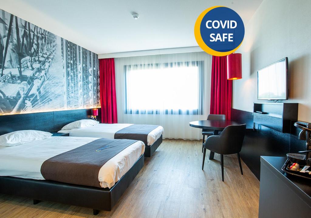 蒂尔堡巴斯琛哥罗普酒店的酒店客房设有两张床和一个可读梳妆保险箱的标志