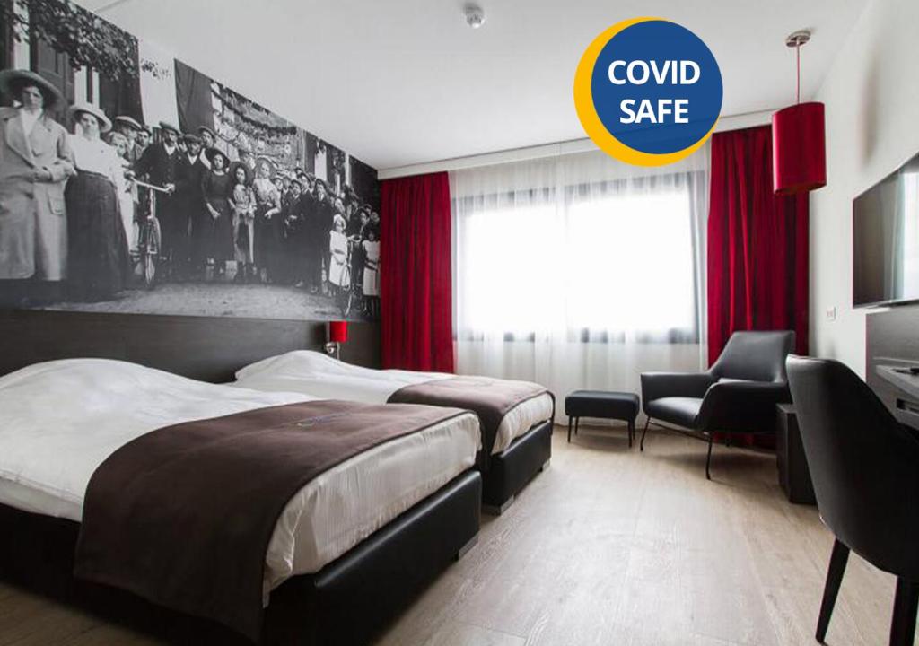 埃因霍温埃因霍温瓦勒巴斯蒂昂酒店的酒店客房设有两张床和一个可读取冷保险箱的标志