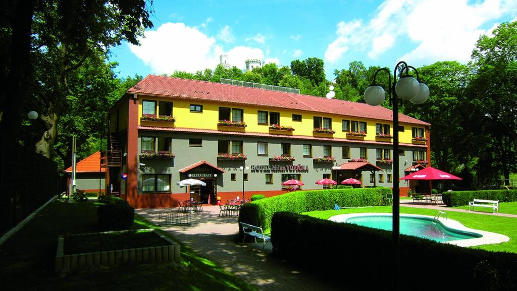 伏尔塔瓦河畔赫卢博卡米兰伏皮卡酒店的一座大型建筑,前面设有一个游泳池