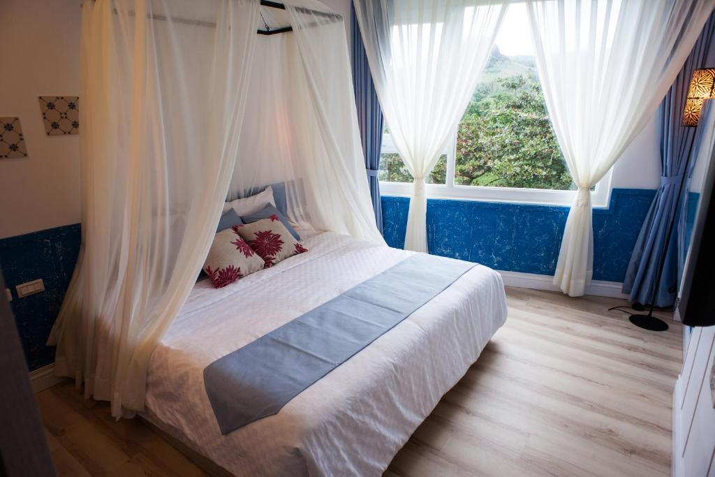 垦丁大街合欢八宿的一间卧室配有带窗帘的床和窗户