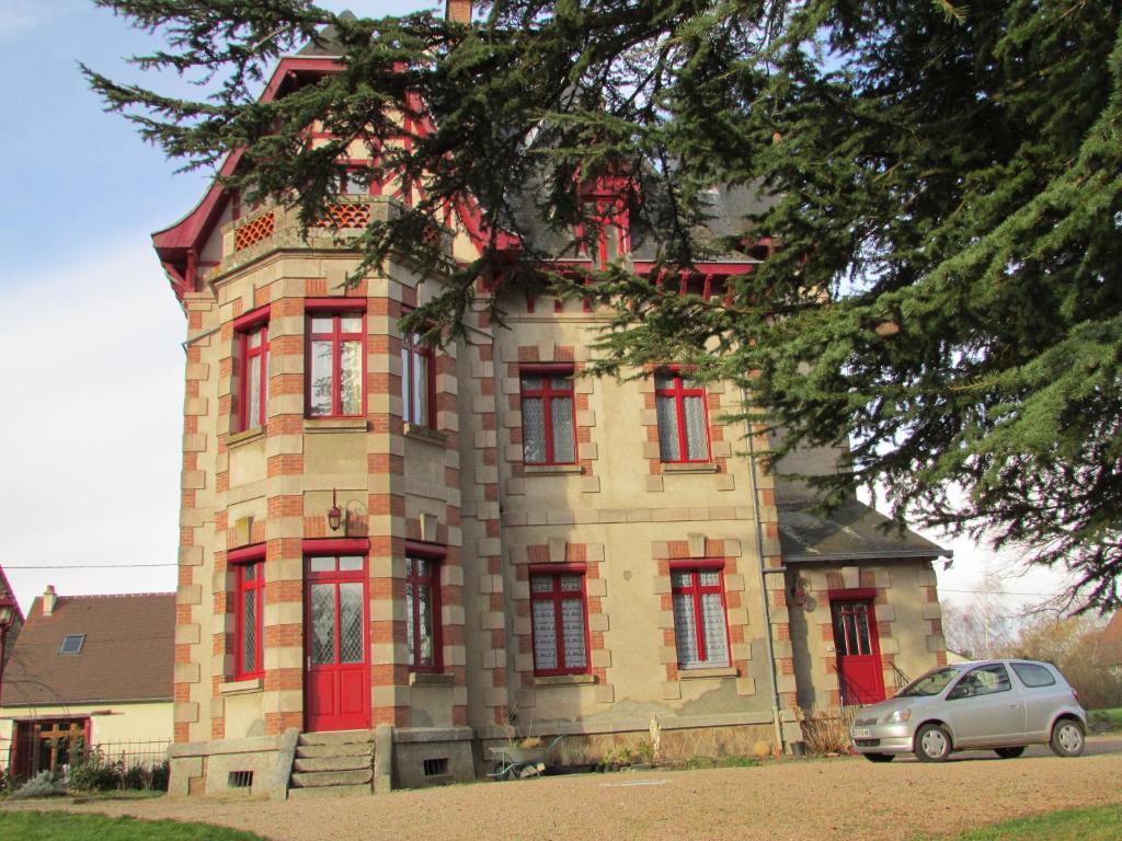 拉苏特兰莱扎城堡住宿加早餐旅馆的一座建筑,有红色的窗户,前面有一辆汽车