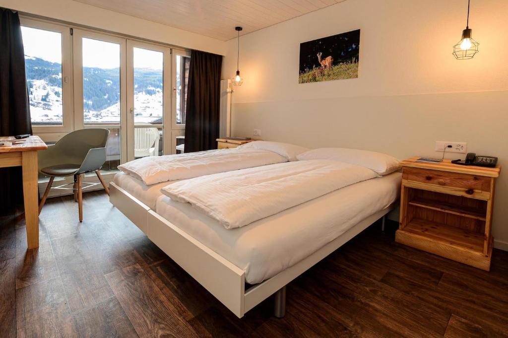 格林德尔瓦尔德瑞士山圣母峰洛奇酒店的一间卧室配有一张大床、一张桌子和一把椅子