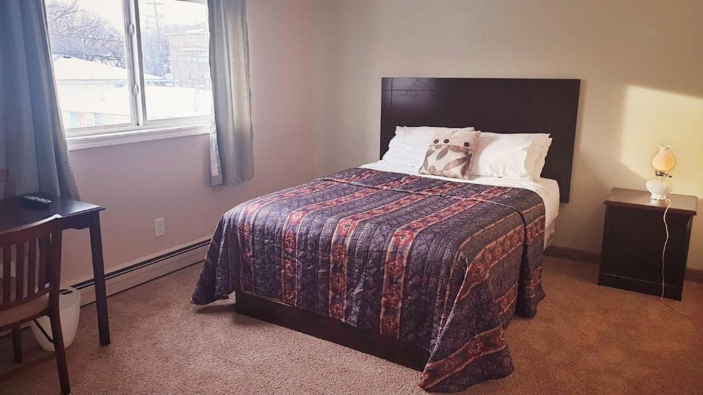 萨斯卡通BUDGET LODGE的一间卧室配有一张带毯子的床和窗户