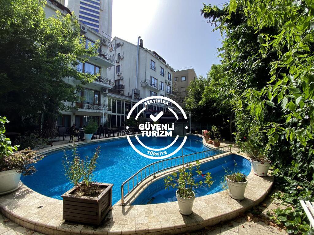 伊斯坦布尔Villa Blanche Hotel SPA & Garden Pool的一座游泳池,在一座建筑前有标志