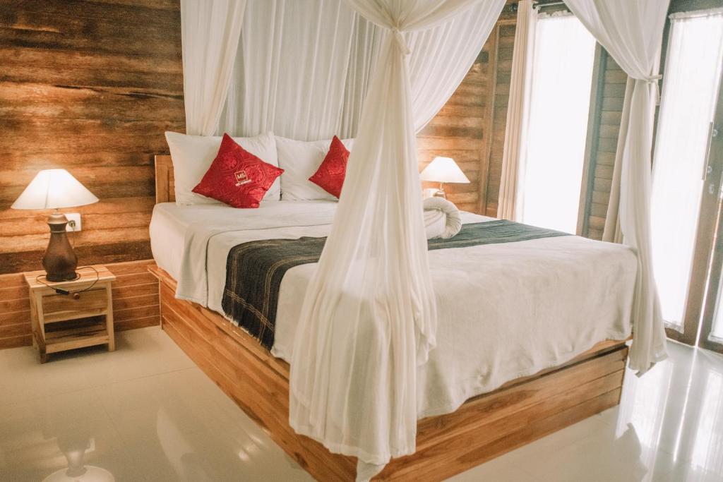 珀尼达岛Mertasari Bungalows的一间卧室配有带白色床单和红色枕头的床。